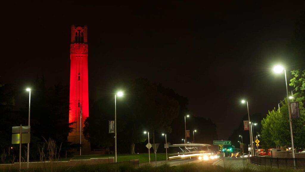 The famous NC State belltower lit red by night in celebration.