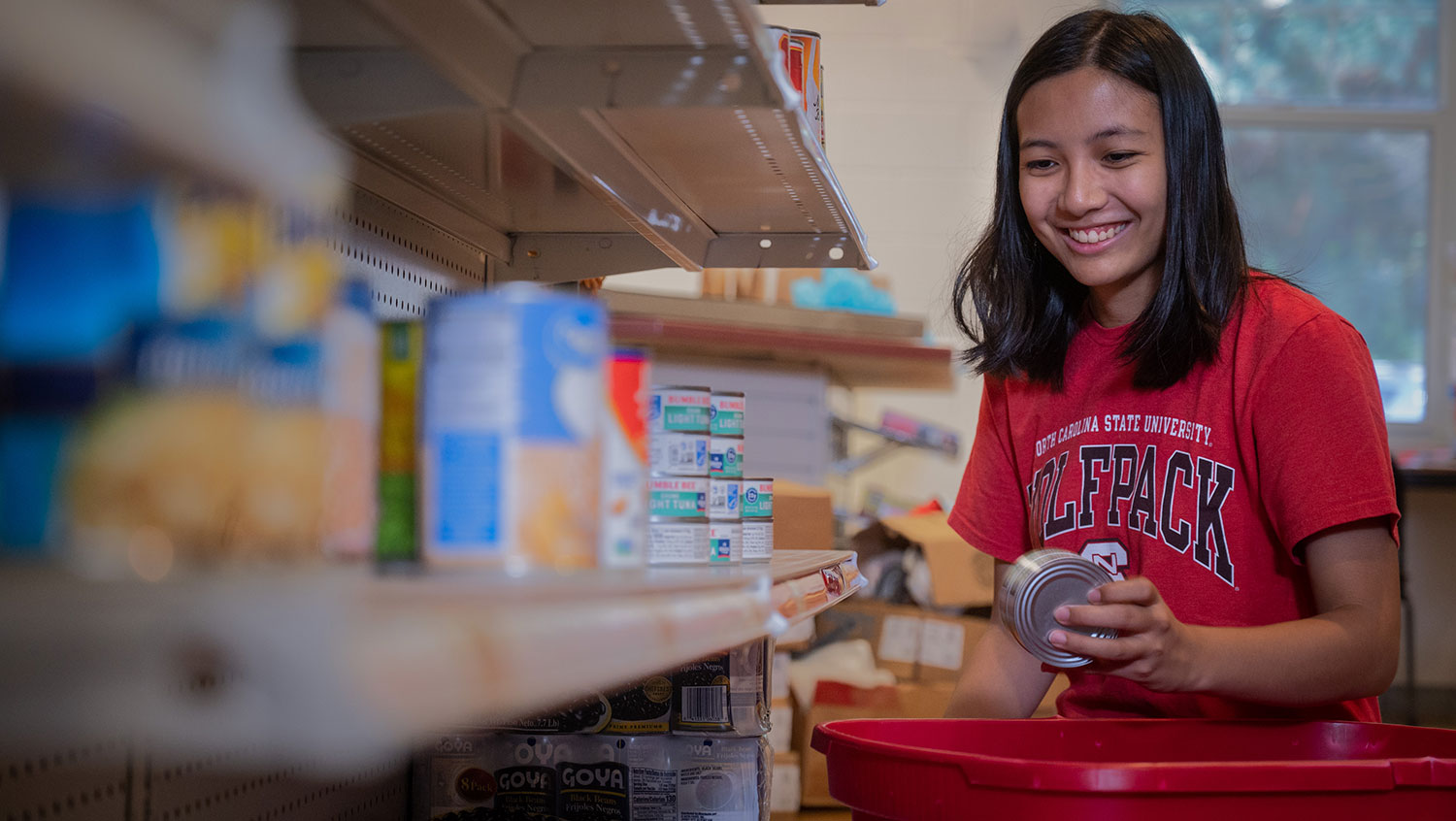 A student unpacks items onto shelves in NC State's on-campus food pantry, Feed the Pack.